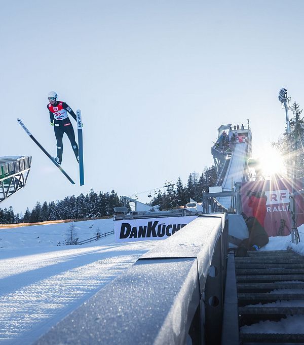 Nordic Combined Triple Seefeld 2025_Skispringer in der Luft mit Sonnenstern näher