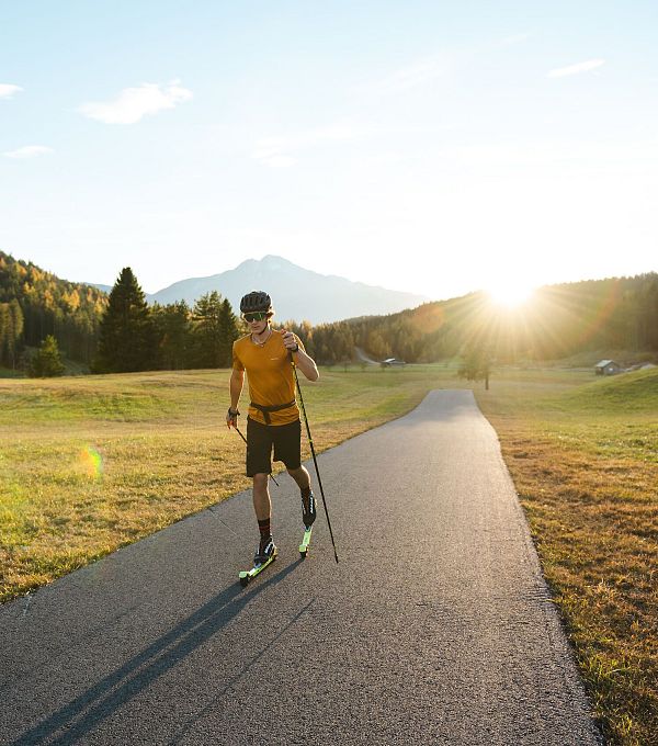 Läufer mit Stöcken auf einem Weg in der Region Seefeld bei Sonnenuntergang.