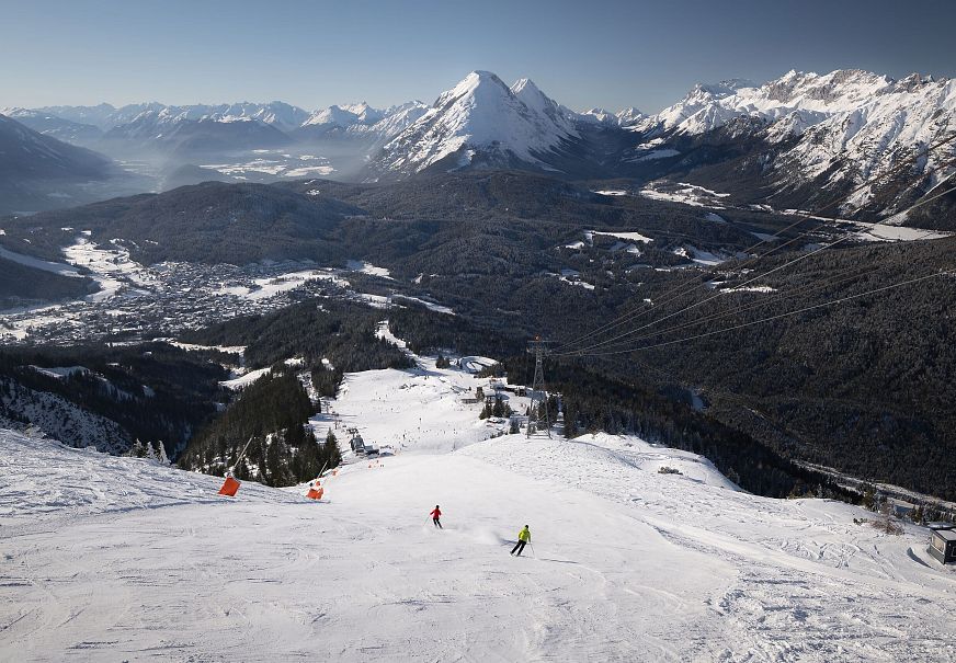 Skifahrerin an der Rosshütte - zwei Skifahrerinnen auf Abfahrt von der Bergstation mit Blick auf Hohe Munde