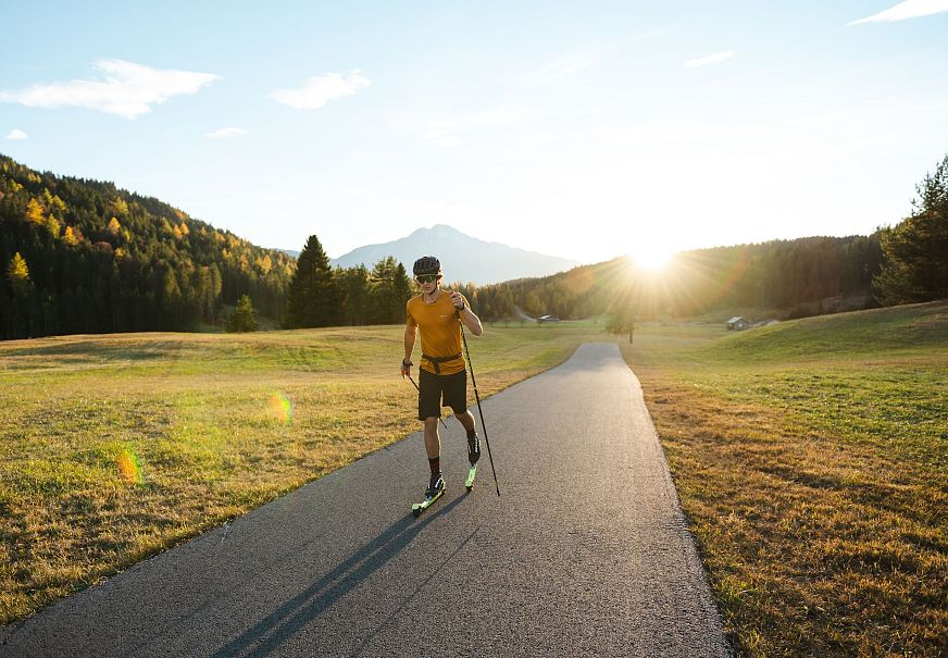 Läufer mit Stöcken auf einem Weg in der Region Seefeld bei Sonnenuntergang.