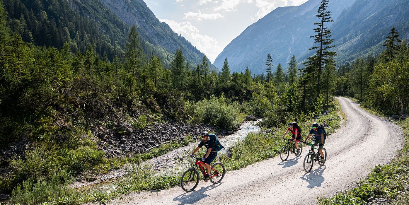 Mountainbiker in den Bergen der Region Seefeld auf einer Schotterstraße, umgeben von Wald und Gebirge.