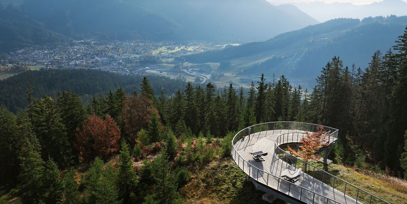 Aussichtspunkt in der Region Seefeld mit Panoramablick auf die Berge und das Tal, umgeben von dichten Wäldern.