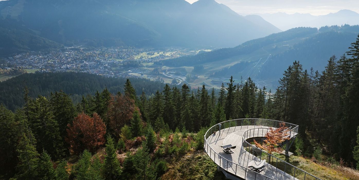 Aussichtspunkt auf einem Hügel mit Blick auf Berge und Tal, umgeben von Wäldern.