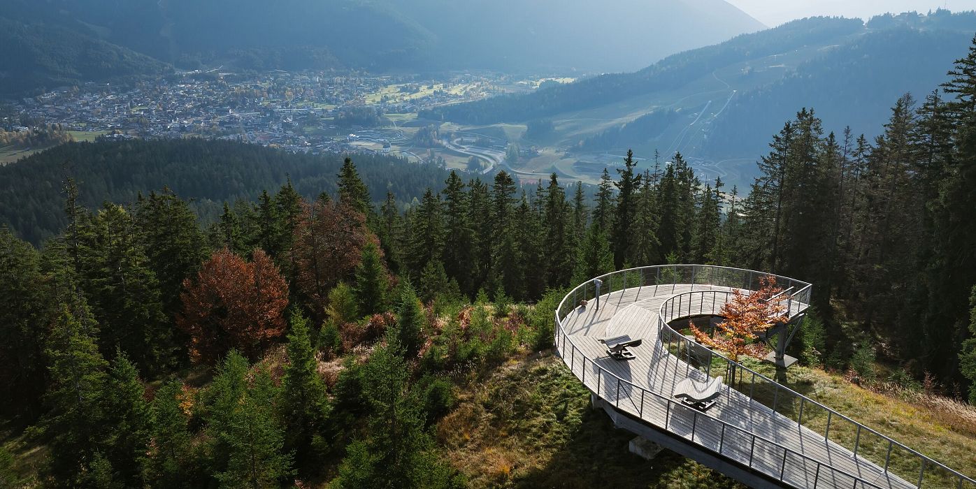 Aussichtspunkt in der Region Seefeld mit Panoramablick auf die Berge und das Tal, umgeben von dichten Wäldern.