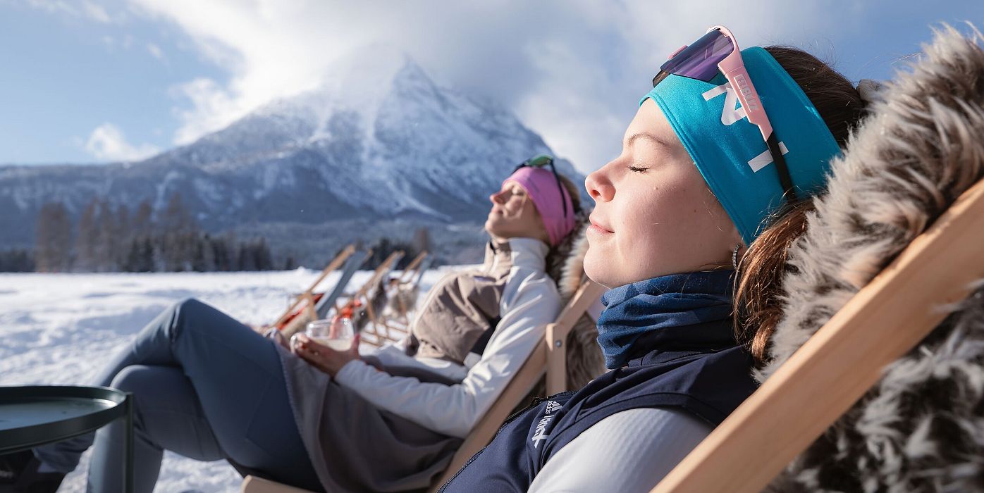 Einkehr bei der J&#39;auszeit Hütte_zwei Frauen genießen die Sonne auf Liegestühlen_Hohe Munde im Hintergrund