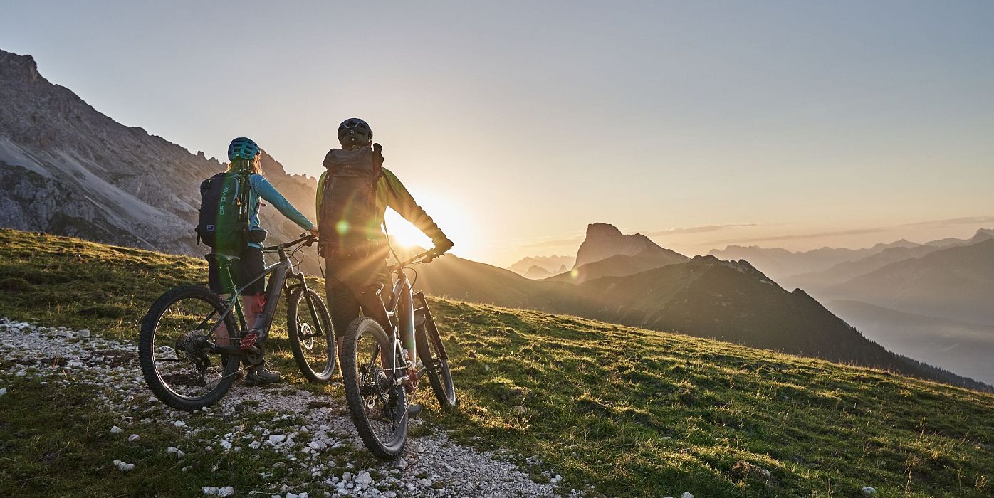 Radfahrer bei Sonnenaufgang in der Region Seefeld, Berge im Hintergrund. Mountainbiken im Morgenlicht.