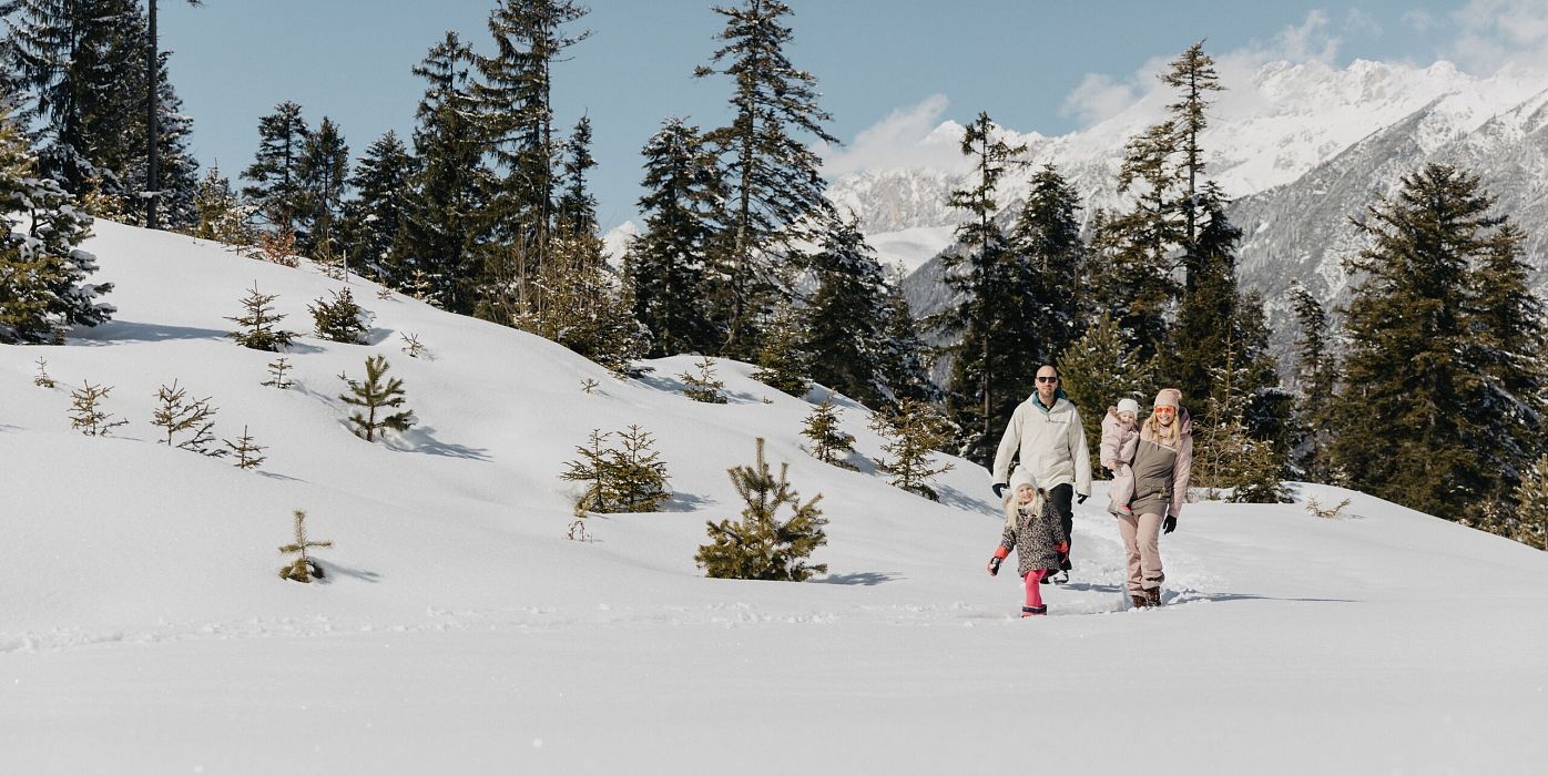 Verschneite Winterlandschaft in der Region Seefeld mit zwei Personen. Tannenbäume und weiße Berge im Hintergrund.