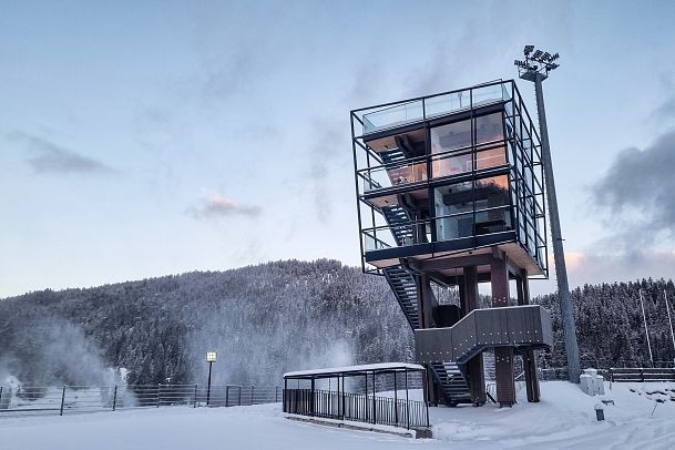 A modern glass observation tower in a snowy landscape.