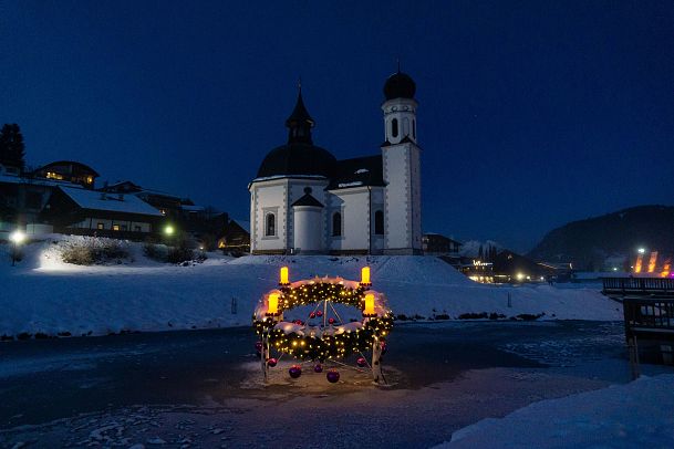 Kirche im Winter bei Dämmerung, geschmücktes Floß auf dem Wasser.