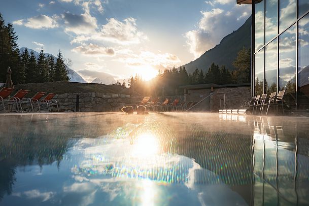 alpenbad-leutasch-im-fruehling-paar-im-outdoor-pool-bei-sonnenuntergangsstimmung-nebel-auf-dem-wasser-8