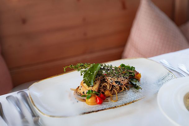 Plate of pasta with herbs and vegetables, elegantly presented on a white dish.
