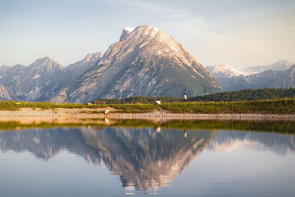 Drohnenaufnahme Gschwandtkopf Speichersee - Person läuft entlang des Speichersees mit Hohe Munde im Hintergrund