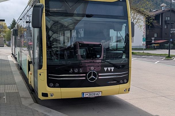 A yellow and black city bus parked at a bus stop.
