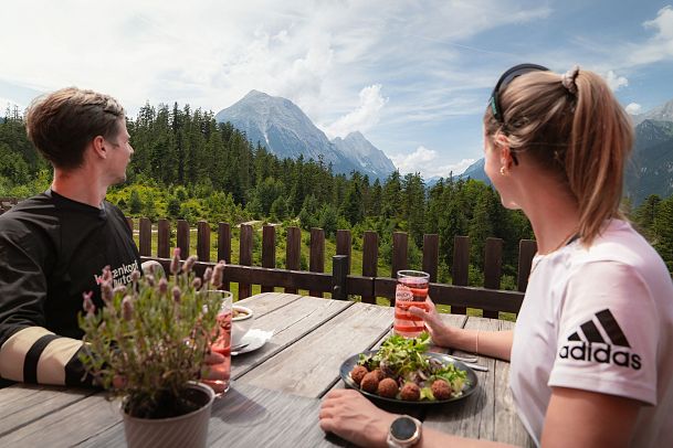 Einkehr in der Katzenkopfhütte im Sommer_Mann und Frau schauen auf Hohe Munde