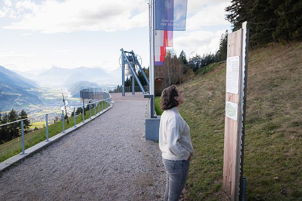 Friedenswanderweg - Frau steht vor Schild an Friedensglocke