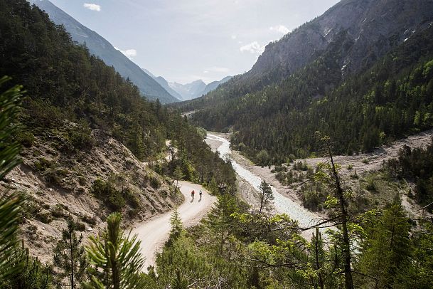 Wanderpfad im grünen Tal der Region Seefeld mit Fluss und Bergen.