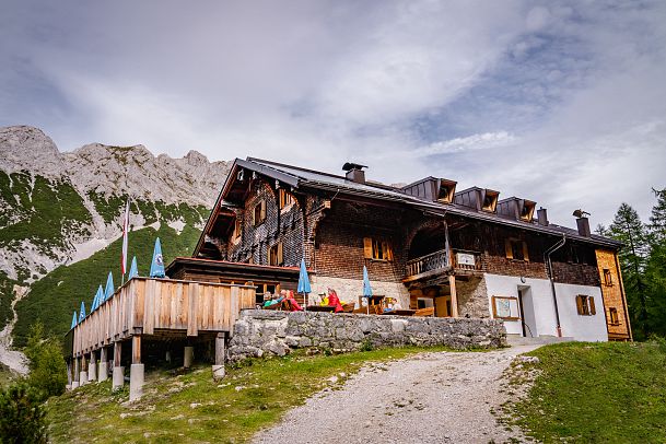 Alpine Hütte mit Holzverkleidung in einer bergigen Landschaft.