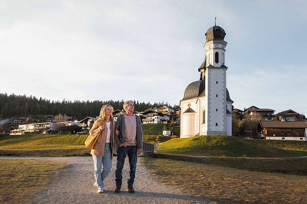 herbstspaziergang-in-seefeld-mann-und-frau-stehen-vor-seekirchl-bei-sonnenuntergangsstimmung-1-2