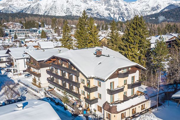 Snow-covered hotel surrounded by mountains in a winter landscape.