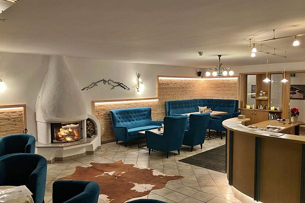 Cozy lounge area with blue seating and a white fireplace, decorated warmly.