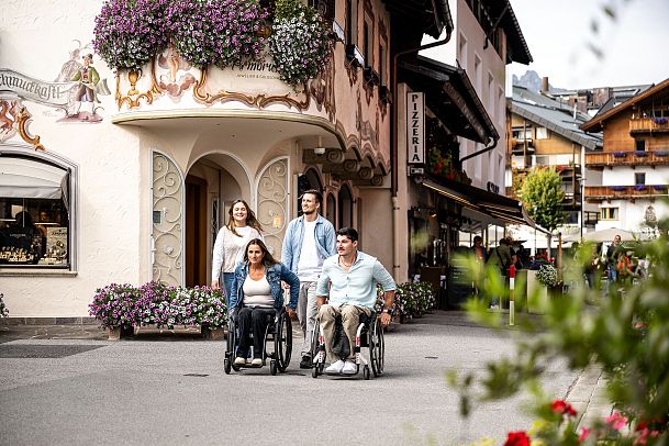 Gruppe mit Rollstühlen in malerischer Straße der Region Seefeld.