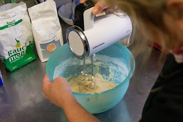 Eine Person mixt Teig in einer Schüssel mit einem Handmixer.