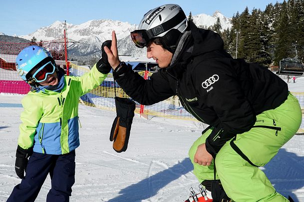 Ein Erwachsener und ein Kind feiern auf der Skipiste mit einem High Five.