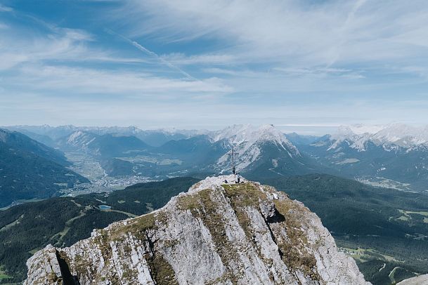 Berggipfel mit Panoramaansicht auf Gebirgen und Täler unter blauem Himmel.