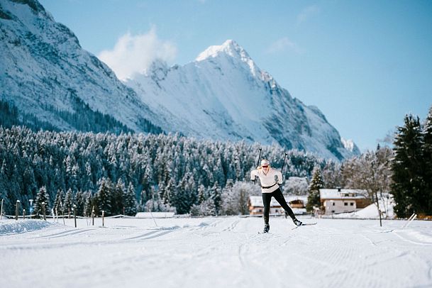 Langlaufen in der Region Seefeld_einzelne Langläuferin auf C9 Plaik Loipe in Leutasch_Zoomaufnahme mit Hohe Wand im Hintergrund (1)
