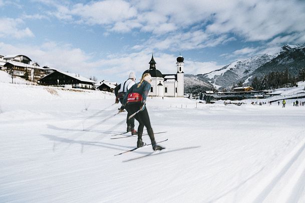 Langlaufen in der Region Seefeld_zwei Langläufer auf A1 Seekirchl Loipe in Seefeld_Langzeitbelichtung_Aufnahme von der Seiten mit Blick auf Seekirchl