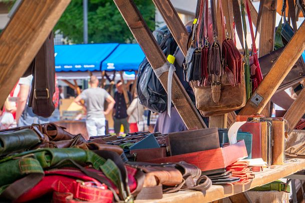 Market stall showcasing various leather goods like bags and belts.