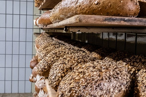 Freshly baked bread loaves with seeds on wooden shelves.