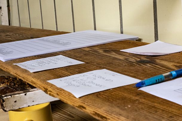 A wooden table with handwritten notes and a blue pen.