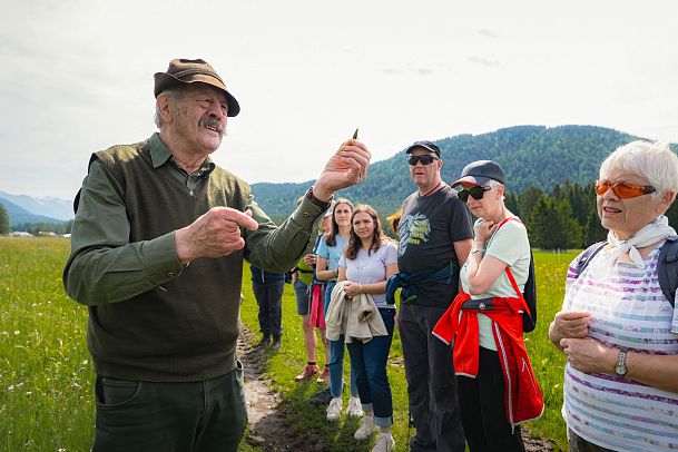 Leutascher Bergfrühlingstage 2025_Wildkräuterwanderung Hungrig auf Natur am Wirtseppelerhof_Hans Neuner zeigt Planze vor Teilnehmer_innen