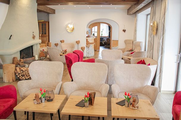 Cozy café interior with armchairs and wooden tables, decorated with flowers.