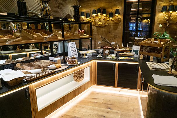 A gourmet buffet featuring various breads and pastries, elegantly displayed in a warmly lit setting.