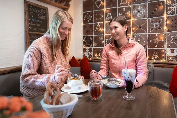 Polis Hütte im Winter_zwei Frauen kehren ein in der Hütte_Frau lächelt andere Frau an