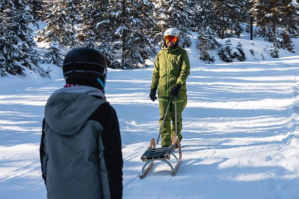 Zwei Menschen auf einer schneebedeckten Piste in der Region Seefeld, einer zieht einen Schlitten durch den Schnee.