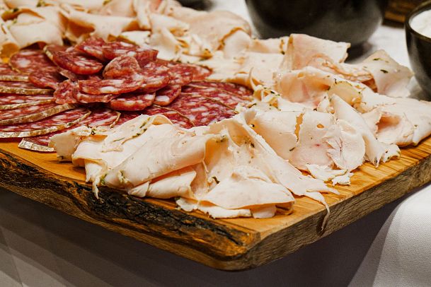 A wooden platter with assorted cold cuts, including turkey and cured sausages.