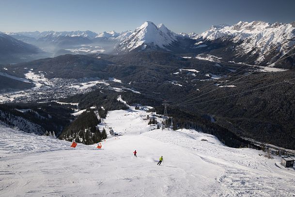 Skifahrerin an der Rosshütte - zwei Skifahrerinnen auf Abfahrt von der Bergstation mit Blick auf Hohe Munde