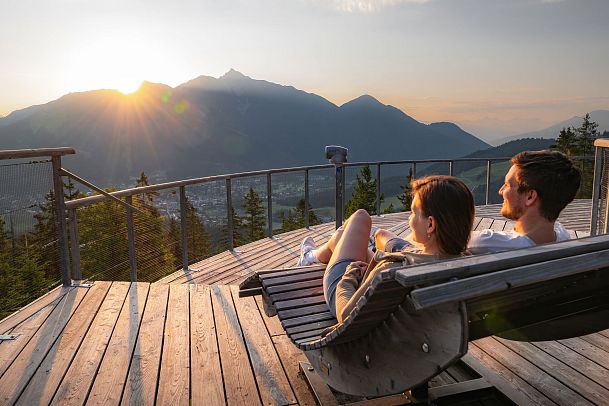 Ein Paar entspannt auf einer Terrasse mit Bergblick in der Region Seefeld bei Sonnenuntergang.