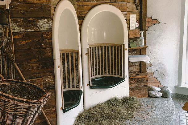 A rustic interior with two curved seating areas and a basket of hay.