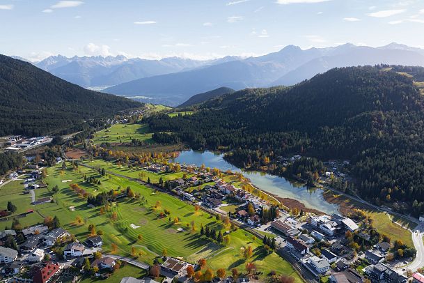 wildsee-im-herbst-drohnenaufnahme-blick-auf-golfplatz-und-see-mit-bergpanorama-1-22
