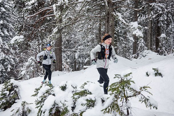 wintertrailrunning-in-der-region-seefeld-abseits-der-wege-zwei-laeuferinnen-im-schnee-mit-wald-im-hintergrund-1