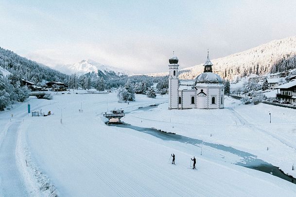 Zwei Langläufer und eine Kirche in der verschneiten Region Seefeld.