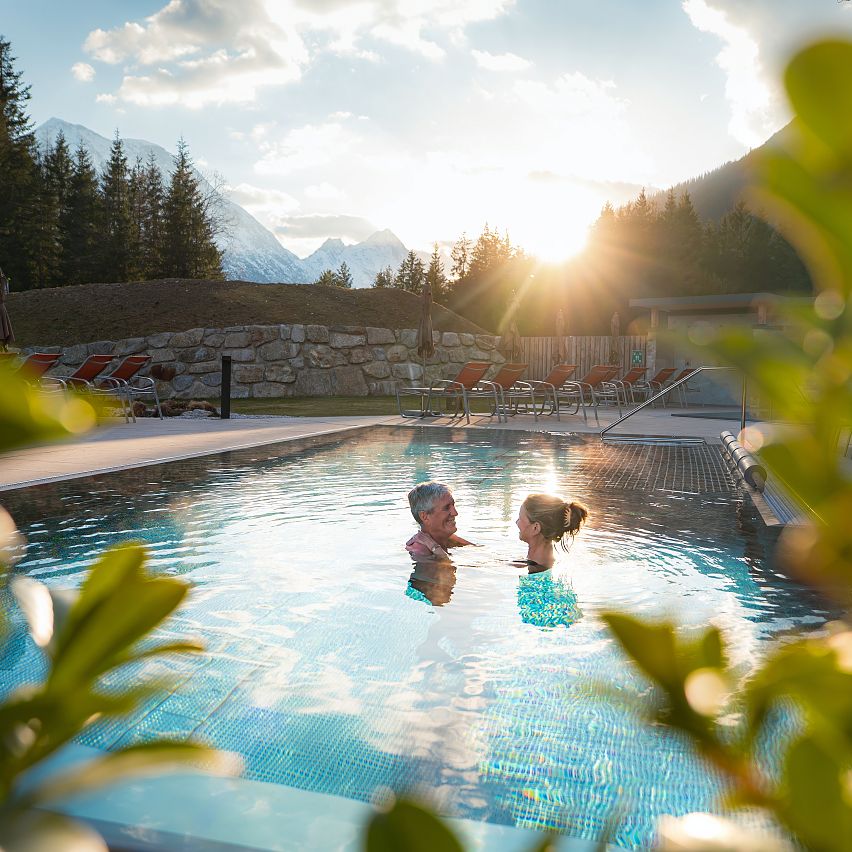 Alpenbad Leutasch im Frühling_Paar schaut sich an im Pool bei Sonnenuntergang (1)