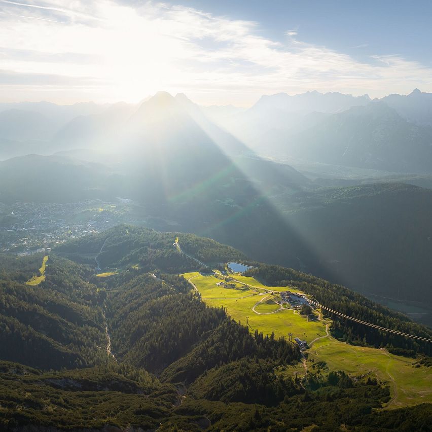 Berglandschaft mit Wiesen und Gipfeln, Sonnenstrahlen durchbrechen die Wolken.