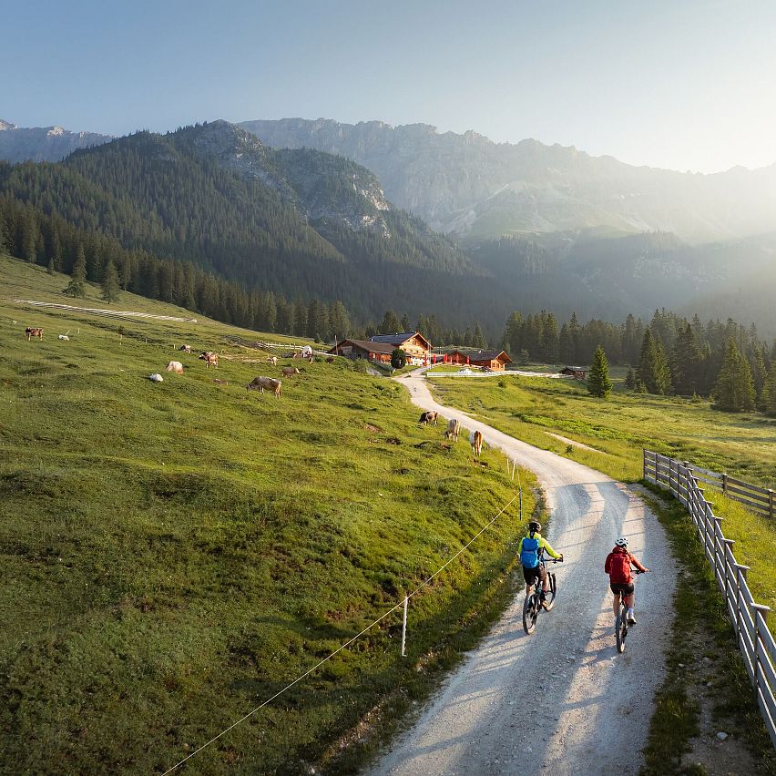 E-Biken im Gaistal im Sommer_Drohnenaufnahme_zwei Biker_innen fahren zur Hämmermoosalm bei Morgenstimmung