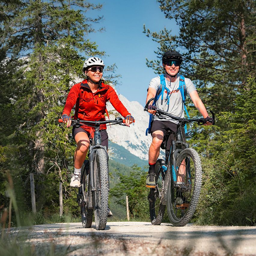 E-Biken im Gaistal im Sommer_zwei Biker_innen auf Forstweg_Aufnahme aus der Nähe