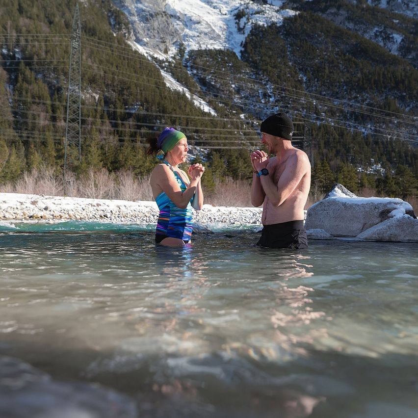 Zwei Personen in einem Naturbecken, eine Frau in Badeanzug und eine Mann in T-Shirt.